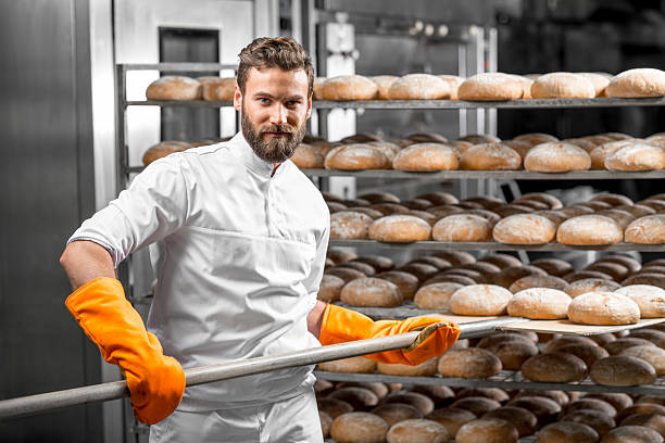 istock Baker putting with shovel bread loafs at the manufacturing 517074484