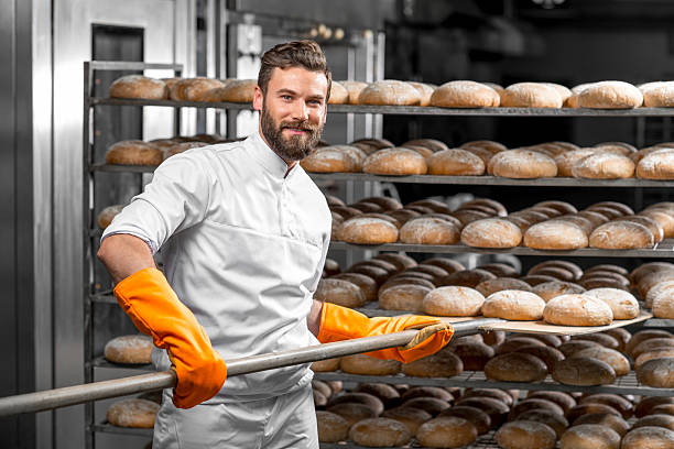 istock Baker putting with shovel bread loafs at the manufacturing 517074556