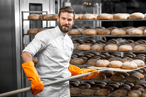 istock Baker putting with shovel bread loafs at the manufacturing 517074696
