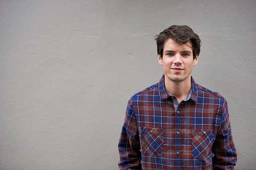 Cropped shot of a young man standing outdoors wearing a plaid shirt