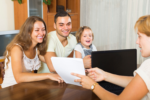 Banking assistant and smiling young family arranging mortgage details. Focus on woman