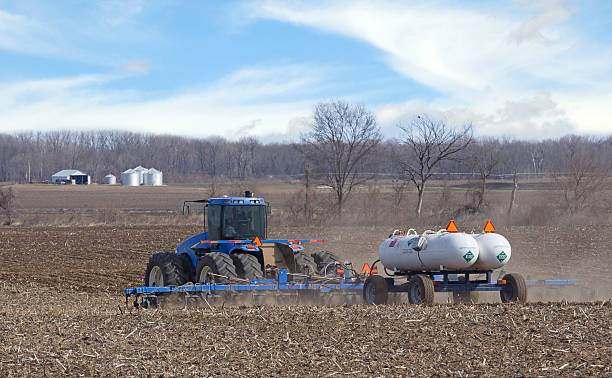 Fertilizing a Farm Field Farm tractor pulling anhydrous ammonia tanks fertilizing farmland ammonia fertilizer stock pictures, royalty-free photos & images