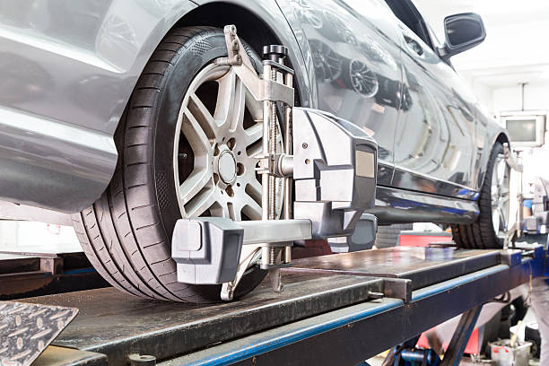 closeup of tire clamped with aligner undergoing auto wheel align - wiel stockfoto's en -beelden