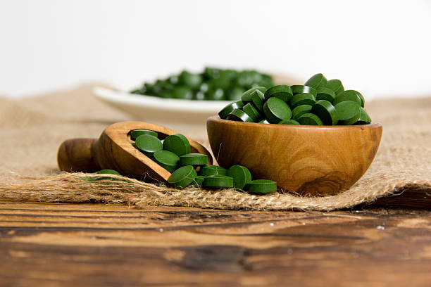 Chlorella pills Photo of bowls and spoon full of chlorella pills on burlap with white space; concept of superfood chlorella stock pictures, royalty-free photos & images