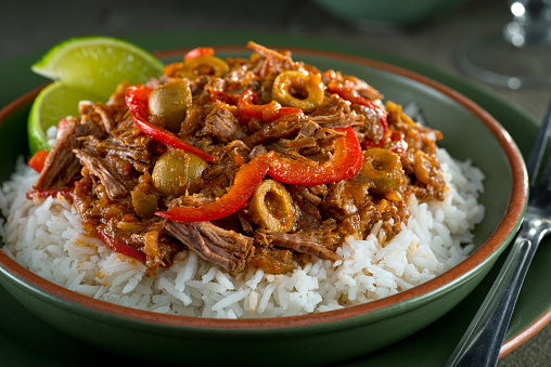 A delicious cuban ropa vieja stew on a bed of rice with lime garnish.