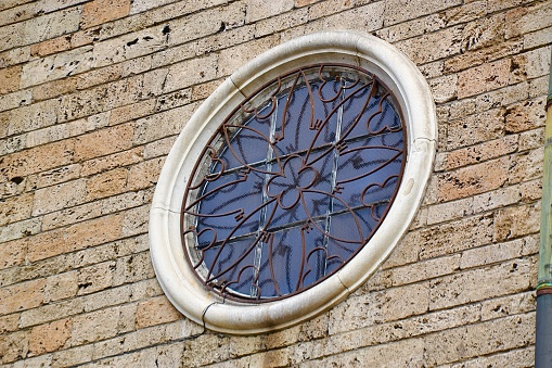 Close up of a grated circular window set into the stone exterior of a historic church in Sofia, Bulgaria