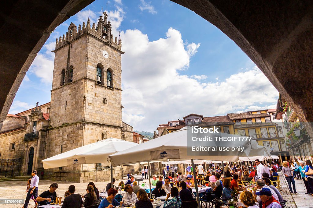 City square restaurants in Guimarães Guimarães, Portugal - October, 5th 2014: An archway view of Guimarães city square, with outdoor restaurants and tourists seen socializing. Guimarães is the leading historical city in Portugal and the center is declared an UNESCO World Heritage Site. Guimarães - Portugal Stock Photo
