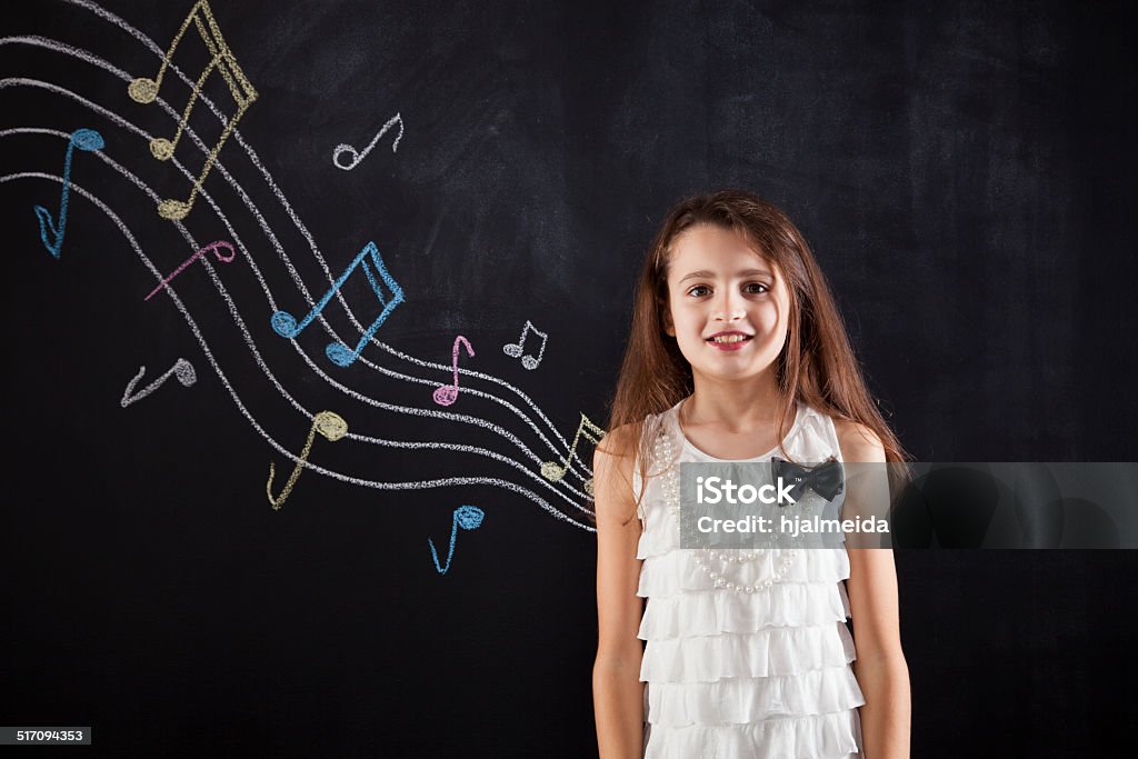 Female child studding music Female studding music next to a blackboard Child Stock Photo