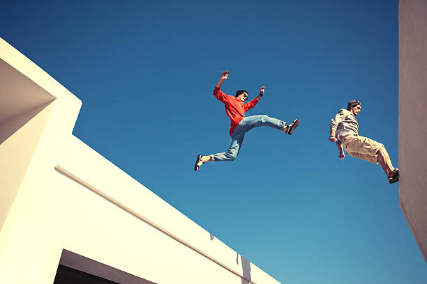 two brave men jumping over the roof stock photo