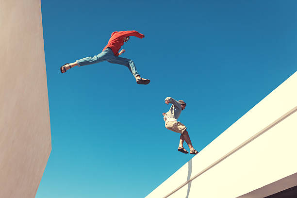 deux hommes courageux sauter sur le toit - parkour photos et images de collection