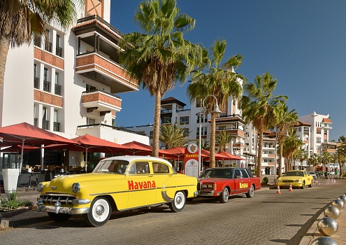 Agar, Morocco - February 17, 2016: The Cuban culture has been transplanted to the Agadir, Morocco marina resort development with a restaurant and these old cars reflecting those seen regularly in Havana. Another symbol of the westernization of a Muslim country and North Africa.