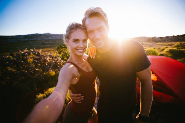 istock Outdoor couple taking sunset selfie while camping on hiking vaca 517104612