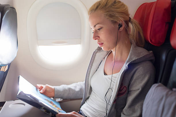istock Woman reading magazine on airplane. 517108734