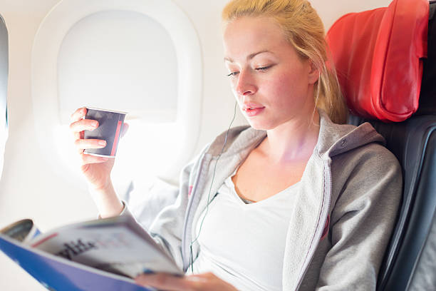istock Woman reading magazine on airplane. 517108850