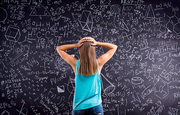 istock Thinking girl holding head against big blackboard, back view 517110000