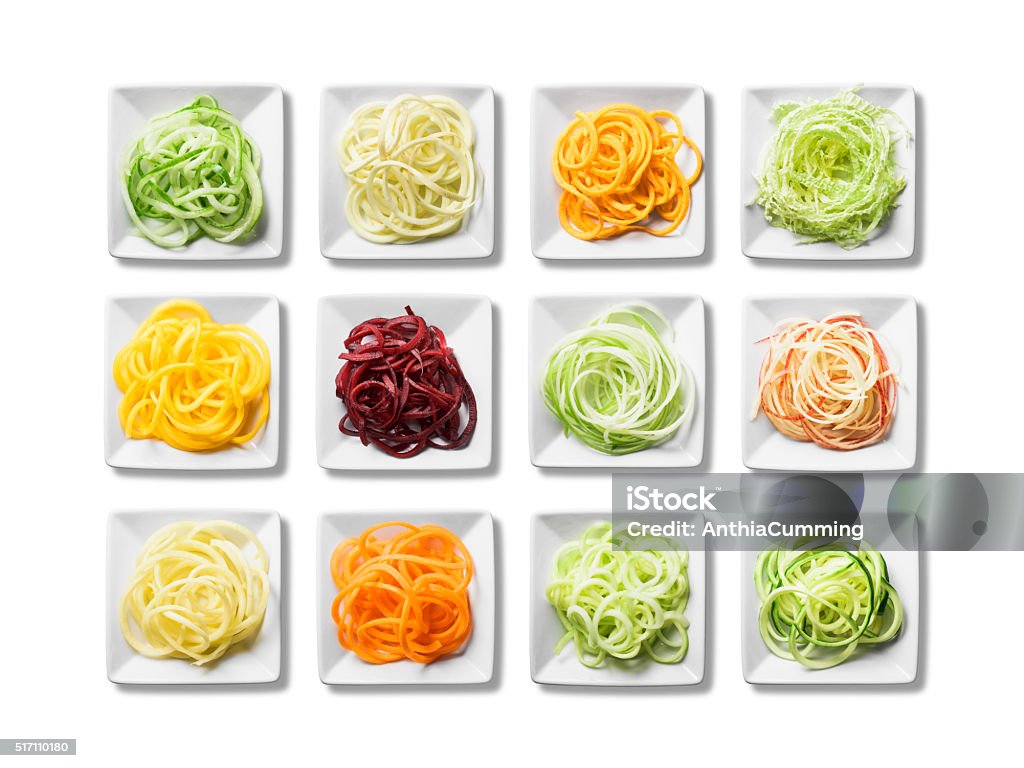 Twelve plates of fresh, bright spiralised fruit and vegetables Small square white plates of spiralised fruit and vegetables are isolated on a white background. The spiraled portions of parsnip, carrot, cucumber, courgette, beetroot, red apple, sweet potato, swede, green apple, cabbage, squash and broccoli are brightly colored. There is a clipping path around the plates and shadows underneath them. Zucchini Stock Photo