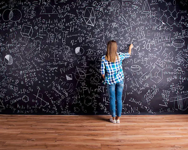 Photo of Student writing on big blackboard with mathematical symbols