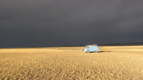 Cardiel, Santa Cruz, Argentina - Febuary 11, 2016: A blue VW Bus from 1973 in the light of the setting sun while a thunderstorm is building up over the pampa of Argentina.
