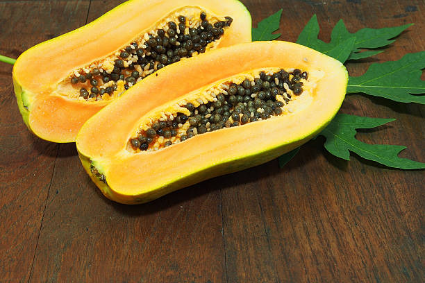 istock Papaya with green leaf on wooden background 517120588
