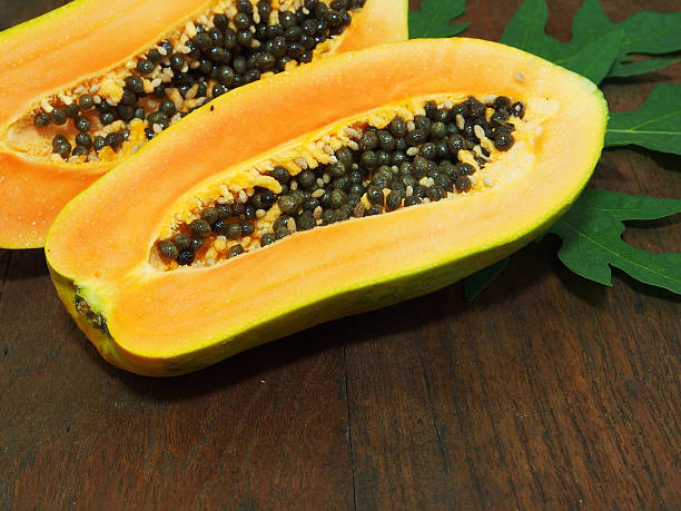 istock Papaya with green leaf on wooden background 517120780