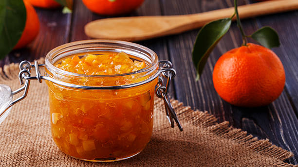 istock Orange (tangerine) jam in a glass jar on the table. 517120924