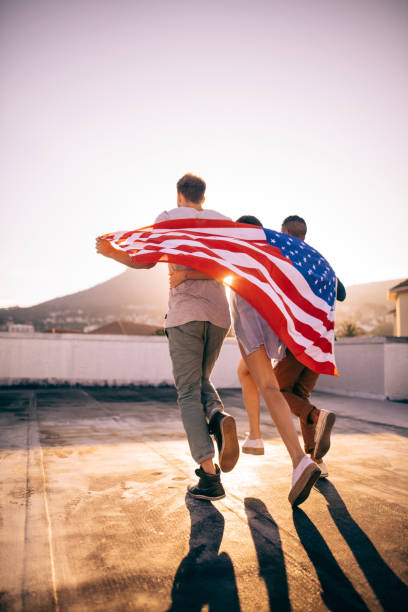 istock Friends embracing wrapped with an American flag on rooftop 517122940