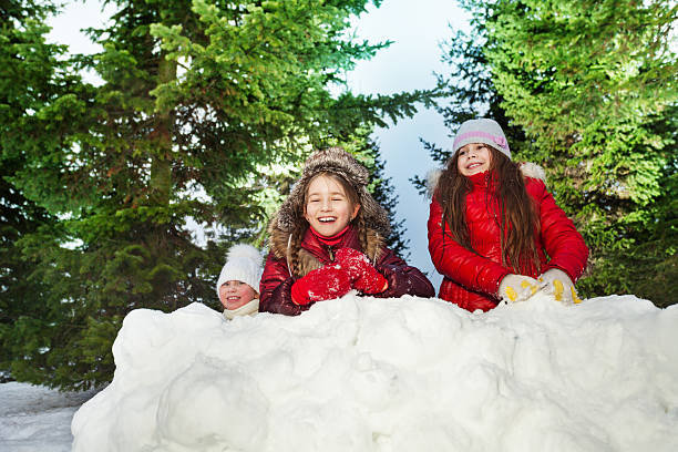 istock Tree girls playing snowballs at sunny winter day 517124986