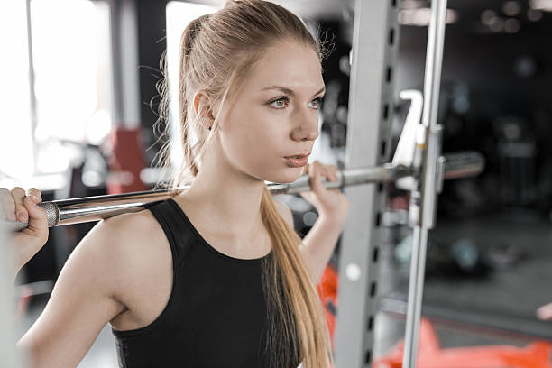 joven mujer rubia haciendo ejercicios con barra para pesas en el gimnasio - clothing the human body long hair blond hair fotografías e imágenes de stock