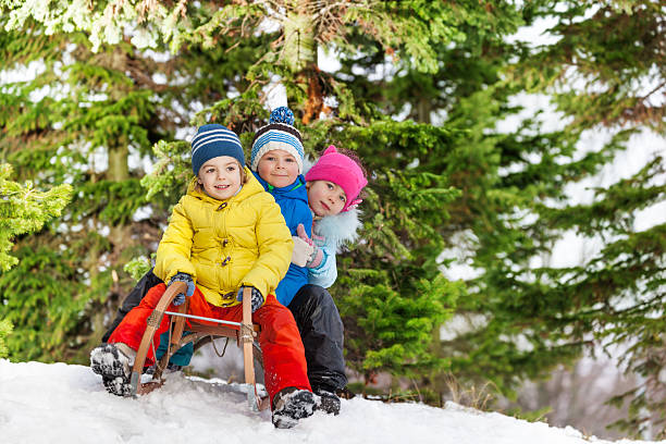 дети маленькие мальчики и девочка слайд на санки - little boys sled clothing slide стоковые фото и изображения