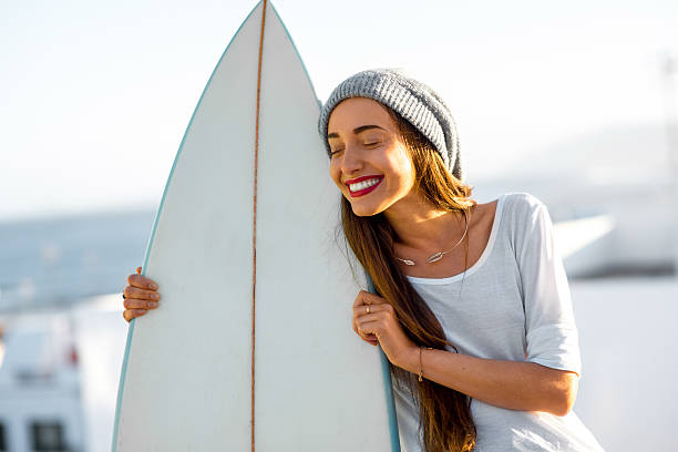 mujer con tabla de surf en el blanco fondo de la ciudad - high key portrait color image travel locations fotografías e imágenes de stock