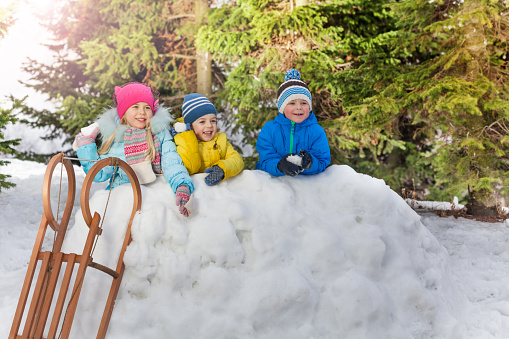 little girl and boy with hats standing in the snow and snowballing together and laughing