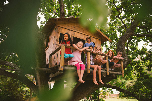 reihe von kindern sitzend auf einem rustikalen baumhaus veranda - baumhaus stock-fotos und bilder