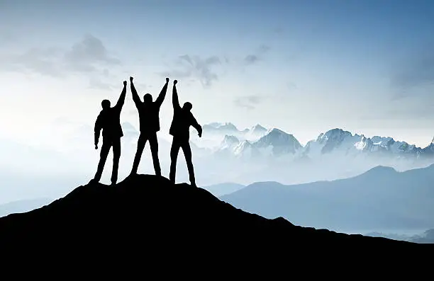 Silhouettes of a team on mountain peak. Sport and active life concept