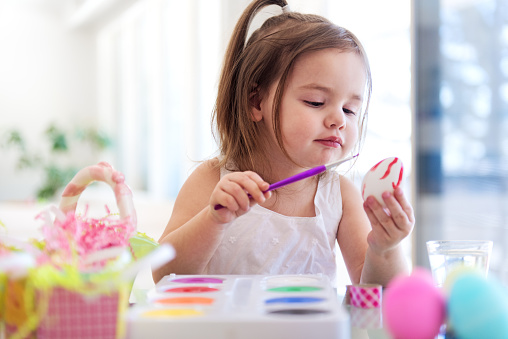 Litte girl painting easter eggs