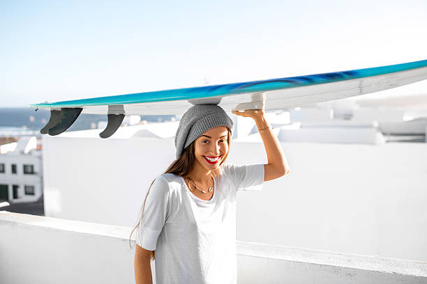 mujer con tabla de surf en el blanco fondo de la ciudad - high key portrait color image travel locations fotografías e imágenes de stock