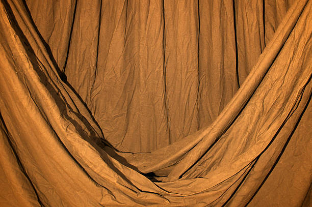 istock Draped black background cloth lit with orange gel 517129696