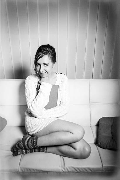 istock woman in sweater holding a book on sofa 517129864