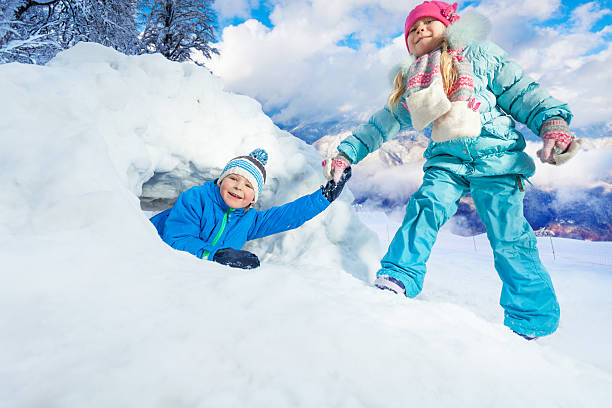 istock Girl pull boy out of snow cave in park 517131070