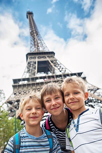 Kids tourists smiling at the camera near Eiffel Tower