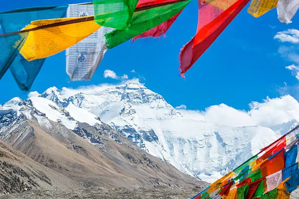 The mighty northface from Mt. Everest, with 8850 m altitude the highest mountain of the world. In the foreground colorful buddhist prayer flags.