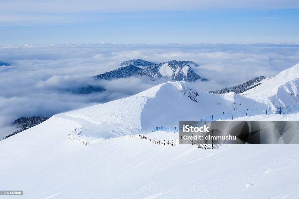 Wooden fence ski trail in caucasus mountains covered with snow Wooden fence and slope ski trail in the caucasus mountains covered with snow and evergreen forest in clouds in Rosa Khutor Ski Resort Krasnaya Polyana Sochi Russia Backgrounds Stock Photo