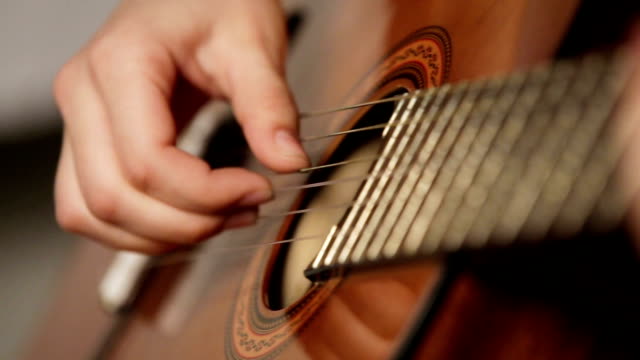 woman's hands playing acoustic guitar