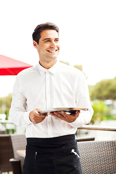 istock Waiter Looking Away While Holding Serving Tray In Restaurant 517148625