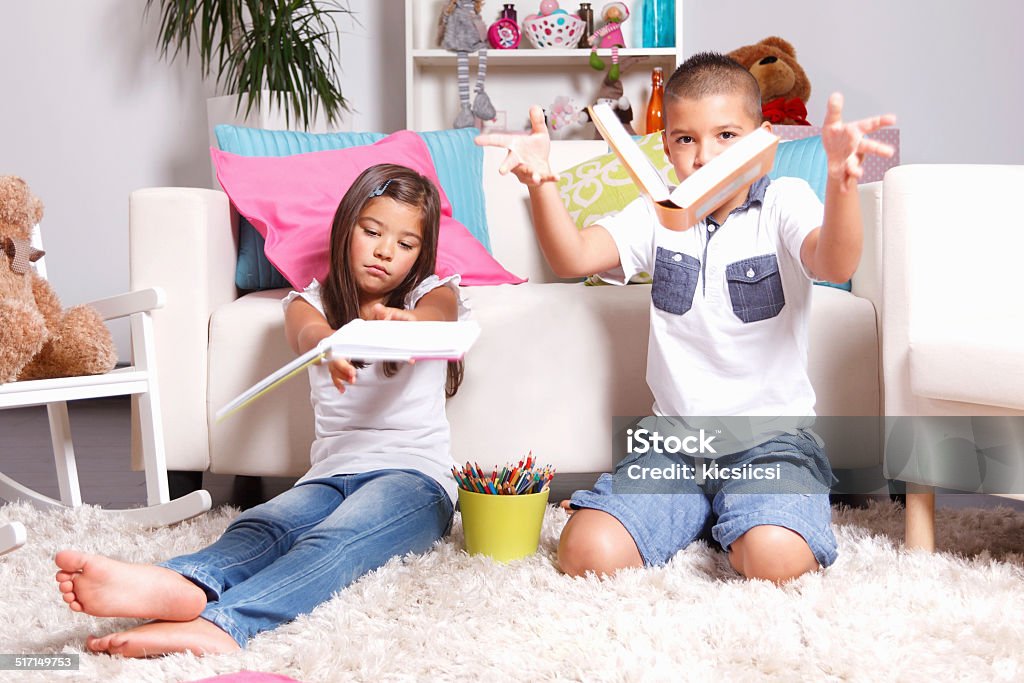 Two young children throwing the books away Portrait of two young children throwing their books away with bored face Activity Stock Photo