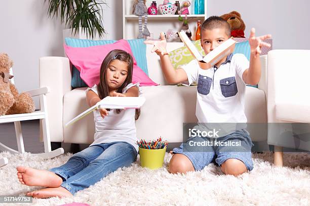 Two Young Children Throwing The Books Away Stock Photo - Download Image Now - Activity, Book, Boredom