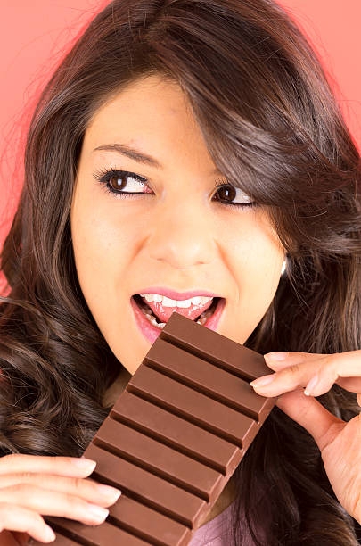 istock beautiful young brunette girl eating chocolate 517151817