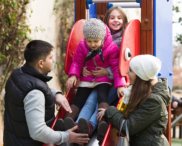 istock parents with two daughters playing at children's slide 517152268