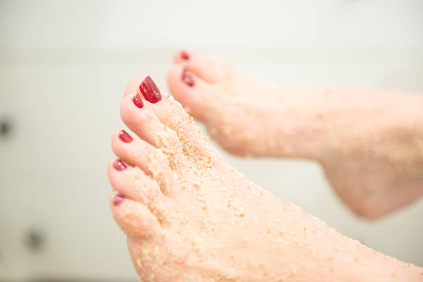 Close-up of Female Feet with Exfoliating Foot Scrub, Red Pedicure stock photo