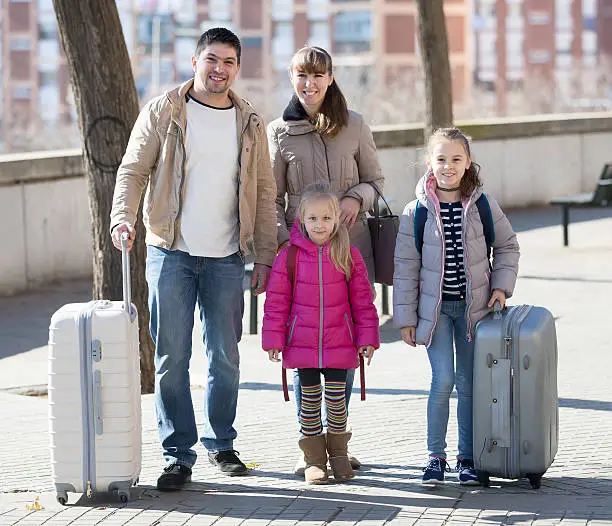 Photo of Family portrait of travellers with wheeled trollers in spring da