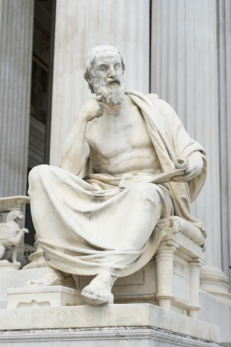 A carved stone statue of a classical philosopher, outside the Austrian Parliament building in Vienna, Austria